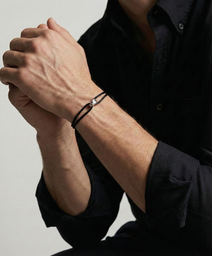 Infinity Black-armband i svart och 925 silver buret på handleden till svart skjorta
