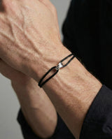 Närbild av silverdetaljen på Infinity Black-armbandets svarta snöre
